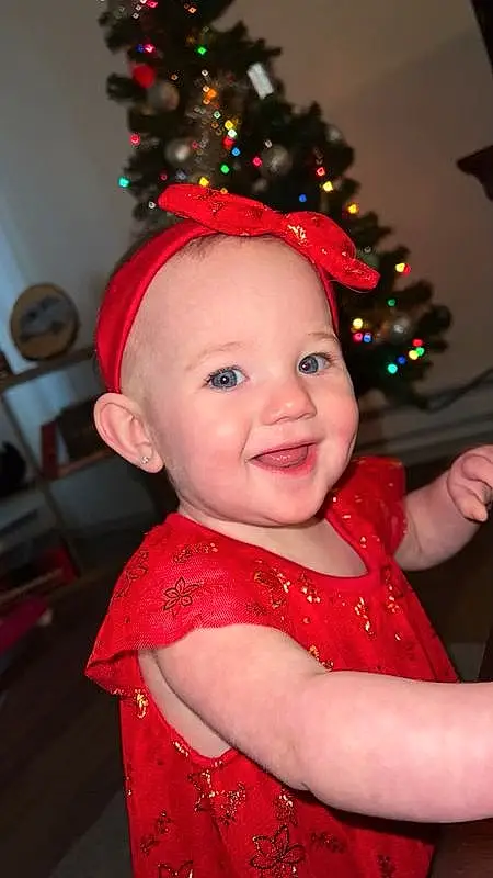 Head, Christmas Tree, Smile, Facial Expression, Christmas Ornament, Standing, Happy, Pink, Toddler, Red, Holiday Ornament, Baby & Toddler Clothing, Fun, Costume Hat, Christmas, Event, Holiday, Christmas Decoration, Tradition, Christmas Eve, Person, Joy