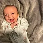 Face, Nose, Cheek, Skin, Head, Lip, Outerwear, Smile, Mouth, Comfort, Baby & Toddler Clothing, Textile, Sleeve, Gesture, Iris, Baby, Flash Photography, Toddler, Happy, Linens, Person
