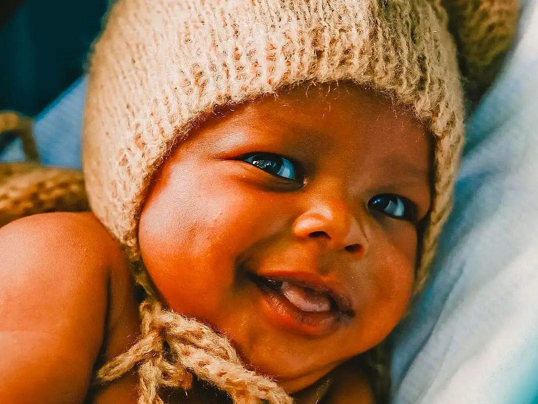 Nose, Cheek, Skin, Lip, Eyes, Facial Expression, Mouth, Smile, Happy, Cap, Iris, Gesture, Toddler, Finger, Baby, Child, Close-up, Fun, Thumb, Knit Cap, Person, Headwear