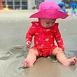 Pink, Body Of Water, Headgear, Beach, Toddler, Happy, Sand, Fun, Child, Foot, Baby & Toddler Clothing, Human Leg, Leisure, Recreation, Sitting, Magenta, Travel, Baby, Fashion Accessory, Person, Headwear